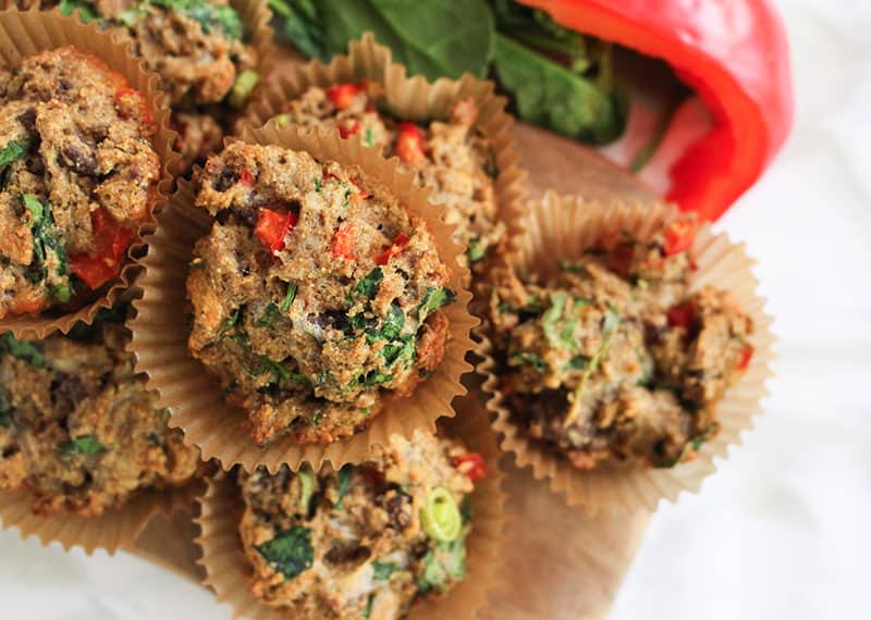 Multiple Savory Muffins are stacked atop a wooden cardboard